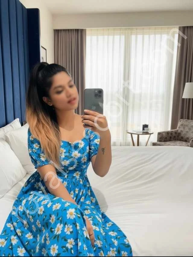 Aarini escort service in mussoorie wearing blue gown and sitting on bed