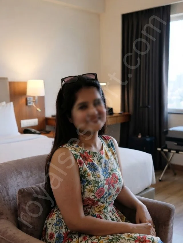 Begur, Bangalore escort service by Inaya wearing flower printed dress and sitting on sofa