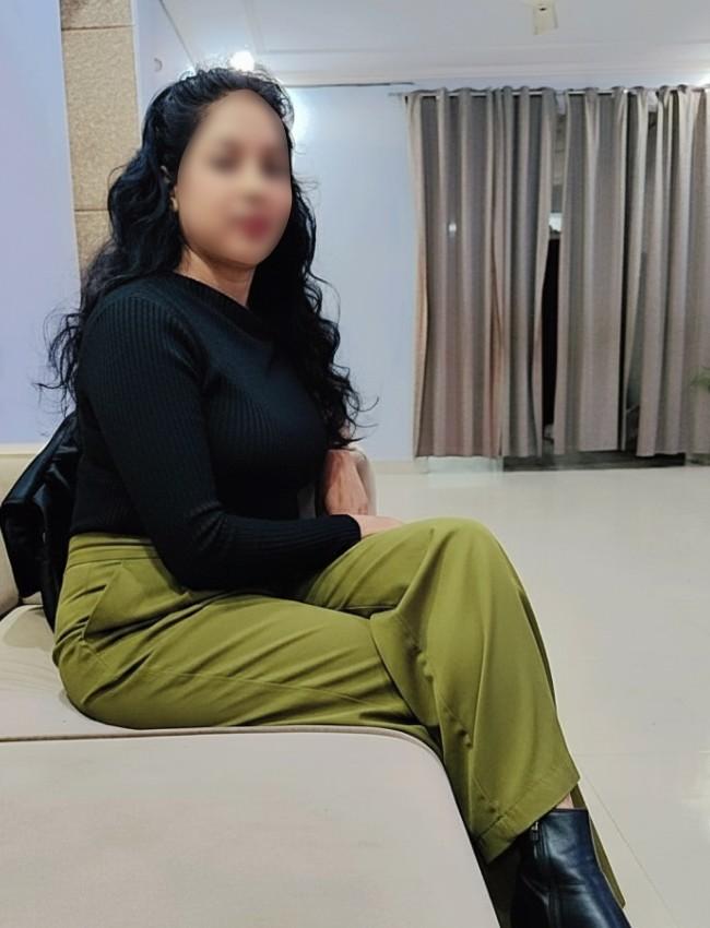 Call Girl Mahnoor sitting on sofa in room wearing jeans and top give side pose