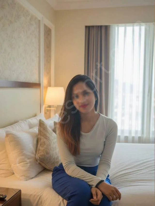 Zirakpur escort by Meher Meher wearing white top and jeans sitting on bed