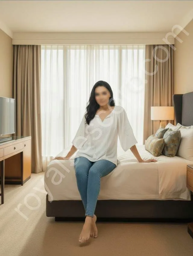 Oorza Zirakpur escort service wearing white top and jeans sitting on bed