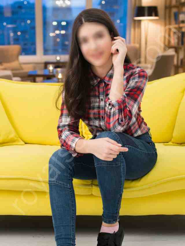 High Profile Escort Pranika wearing jeans and check shirt sitting in sofa