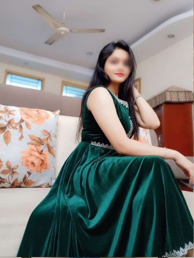 Vamyaa escort in mussoorie sitting in sofa wearing green gown 